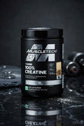 MuscleTech Platinum 100% Creatine unflavoured powder supplement tub on a dark surface.